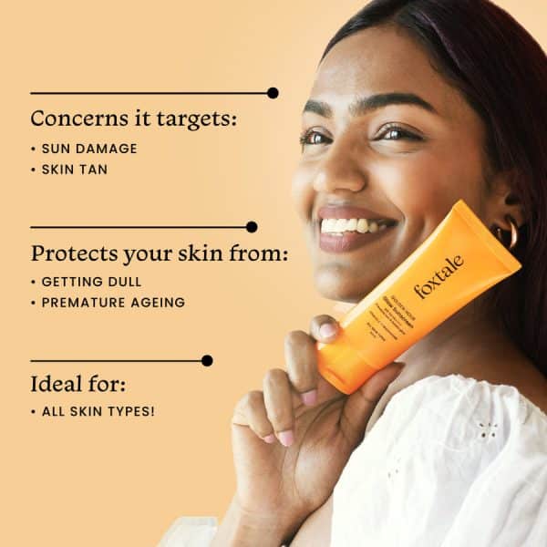 Smiling woman holding a tube of Foxtale Golden Hour Glow Sunscreen SPF 50, emphasizing its protection against sun damage, skin tan, and its suitability for all skin types.